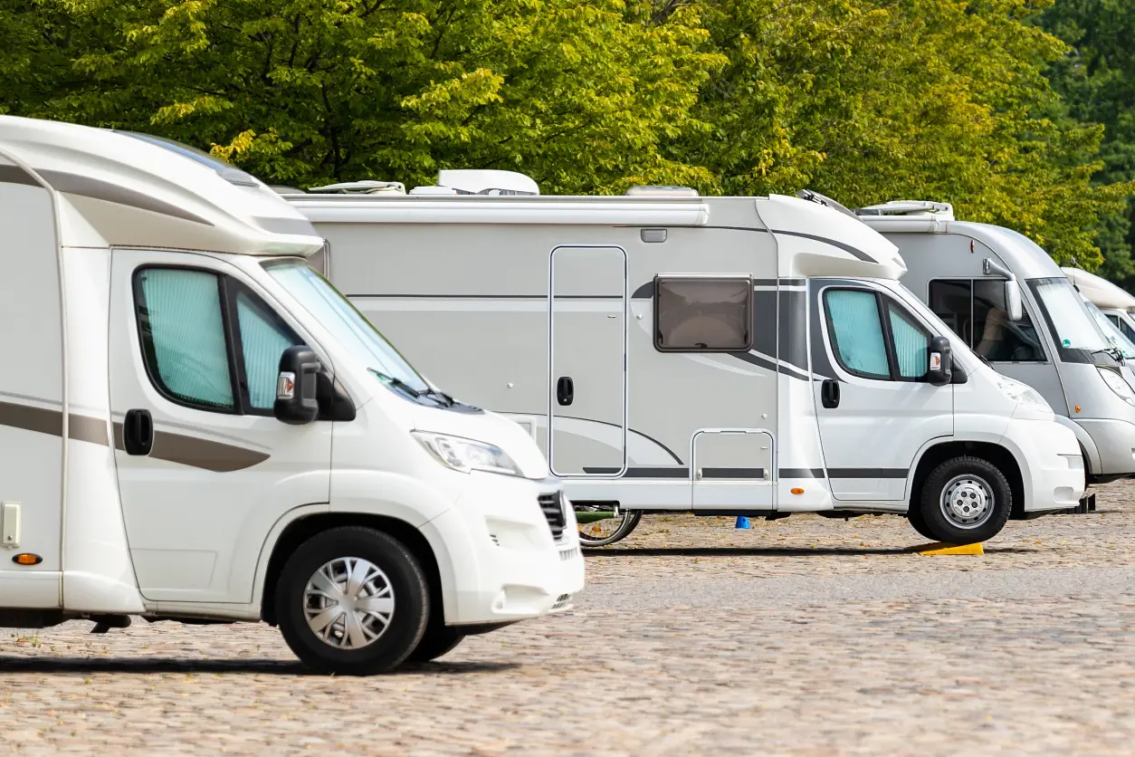 New Project(9) Parked white motorhomes on cobblestone ground.